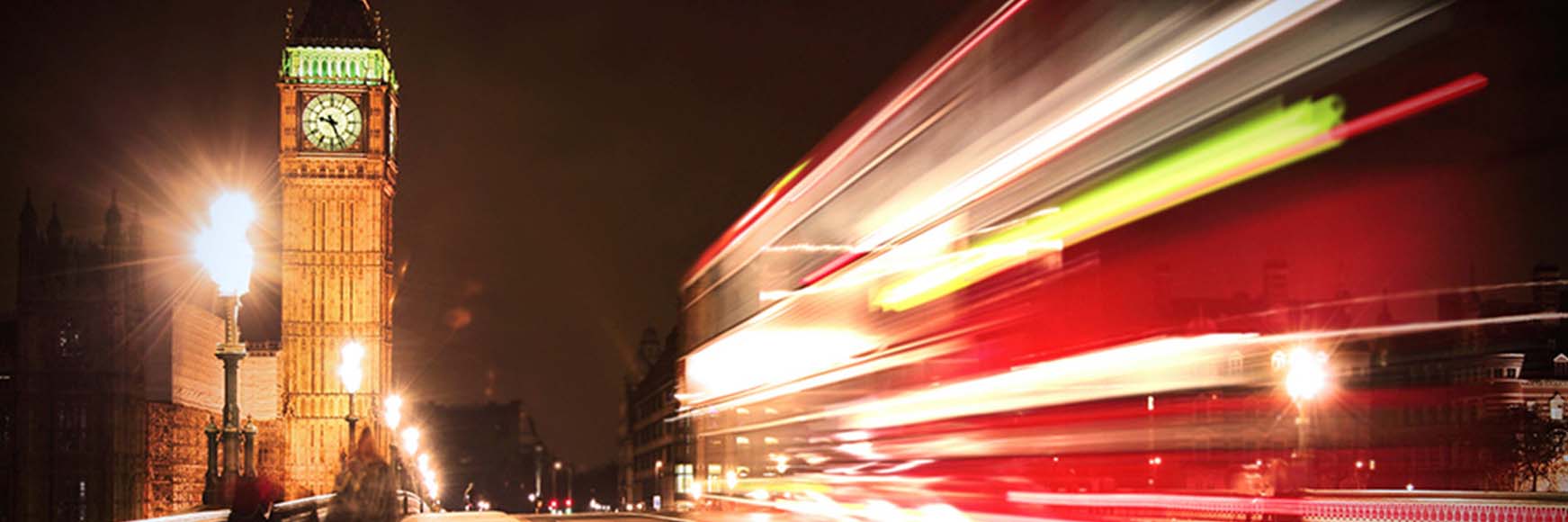 Big ben and a red double decker bus flashing by at night